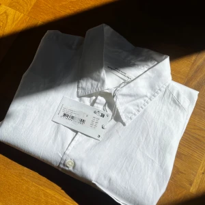 Vit skjorta från Wood Wood - Vit skjorta från Wood Wood i klassisk modell med krage, bröstficka och knappar framtill. Tillverkad i bomull, perfekt för dig som gillar clean och enkel stil. Långärmad och med snygg passform som funkar året runt. Taggen sitter kvar. NYPRIS 1850kr!!