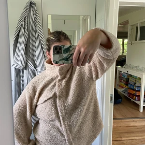 Beige teddyjacka med knappar - Mysig beige teddyjacka från Bik Bok med hög krage och tryckknappar framtill. Jackan har en bröstficka med lock och är i ett fluffigt teddy-material som ger en chill och trendig vibe. Perfekt för lager-på-lager och passar till allt.