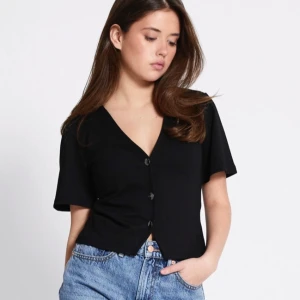 Svart croppad blus med knappar - Svart croppad blus med v-ringning och korta ärmar. Aldrig använd säljer en ljus rosa också🤗