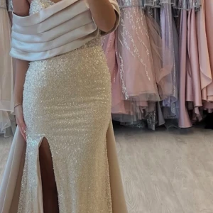 Champagnefärgad glittrig långklänning - Säljer en elegant champagnefärgad långklänning, änvänd endast engång, brudtärna var jag då och nypris 6500. Storlek 40/42, från rever design 