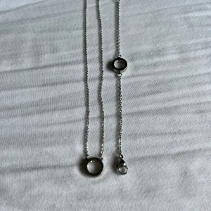 Silverfärgat halsband och armband med cirkelberlocker - Snyggt halsband och armband i silverfärgad metall med stilren cirkelberlock. Kedjan är tunn och har ett klassiskt lås. Perfekt för dig som gillar minimalistisk och modern stil. Passar till alla dina outfits och är lätt att matcha med andra smycken.