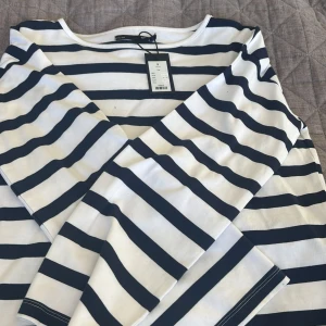 Randig långärmad tröja från lager 157 - Säljer en fräsch långärmad tröja från lager 157 med klassiskt marinblått och vitt randigt mönster. Tröjan har rund hals och är gjord i mjuk bomull, perfekt för chill dagar. Enkel och stilren design som funkar till jeans eller kjol.