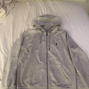 Gråt sett från Polo Ralph Lauren - Snygga grå mjukisbyxor från Polo Ralph Lauren med klassisk logga broderad på benet. Byxorna har ribbade muddar vid benslut, snörning i midjan och sidofickor. Väldigt bra skick ser knappt använd ut 