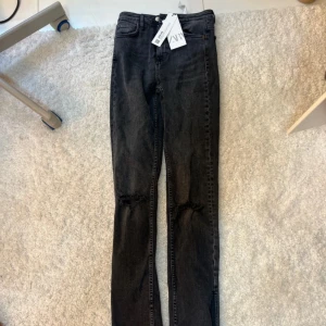 Svarta  jeans från Zara - svarta jeans från Zara med slitna detaljer vid knäna och slits längst ner.  Helt nya med prislapp 