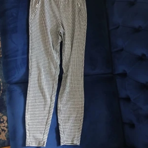 Svarta och vita rutiga byxor Janina - Snygga byxor från Janina i storlek 34 med svart och vitt hundtandsmönster. De har smal passform, dragkedja vid fickan och är tillverkade i ett mjukt material som sitter skönt. 