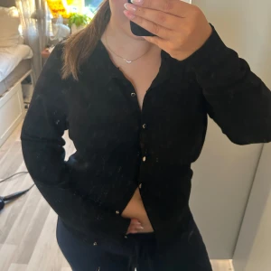 Svart långärmad skjorta Holly & Whyte - Svart långärmad skjorta från Holly & Whyte by Lindex i storlek L. Skjortan har klassisk krage och knappar framtill. Materialet är mjukt och känns som bomull, perfekt för en chill och stilren look och passar till allt. 