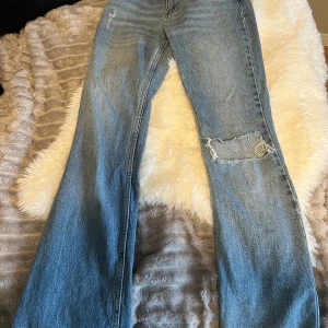 Ljusblå raka jeans med slitningar - Säljer ett par ljusblå jeans med raka ben och snygga slitningar på knäet och vid fickan. Har dock en liten defekt på bakfickan men inget stort.