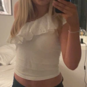 Vit one shoulder topp  - Säljer en söt vit ärmlös topp med volangdetaljer. Perfekt för sommardagar och kan enkelt matchas med olika outfits. Vet inte märket på toppen då den köptes i Polen!🥰