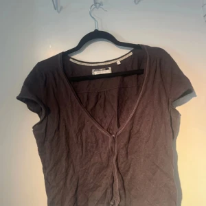 Brun topp från Marc O'Polo - Säljer en  topp från Marc O'Polo med korta ärmar och v-ringning. Toppen har en dragkedja framtill och är tillverkad i ett mjukt material.
