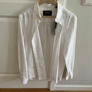 Vit skjorta från Lyle & Scott - Säljer en stilren vit skjorta från Lyle & Scott i storlek M. Aldrig använt skjortan! Skjortan är tillverkad i lättviktigt bomullsmaterial och har en klassisk design med knappar framtill. 