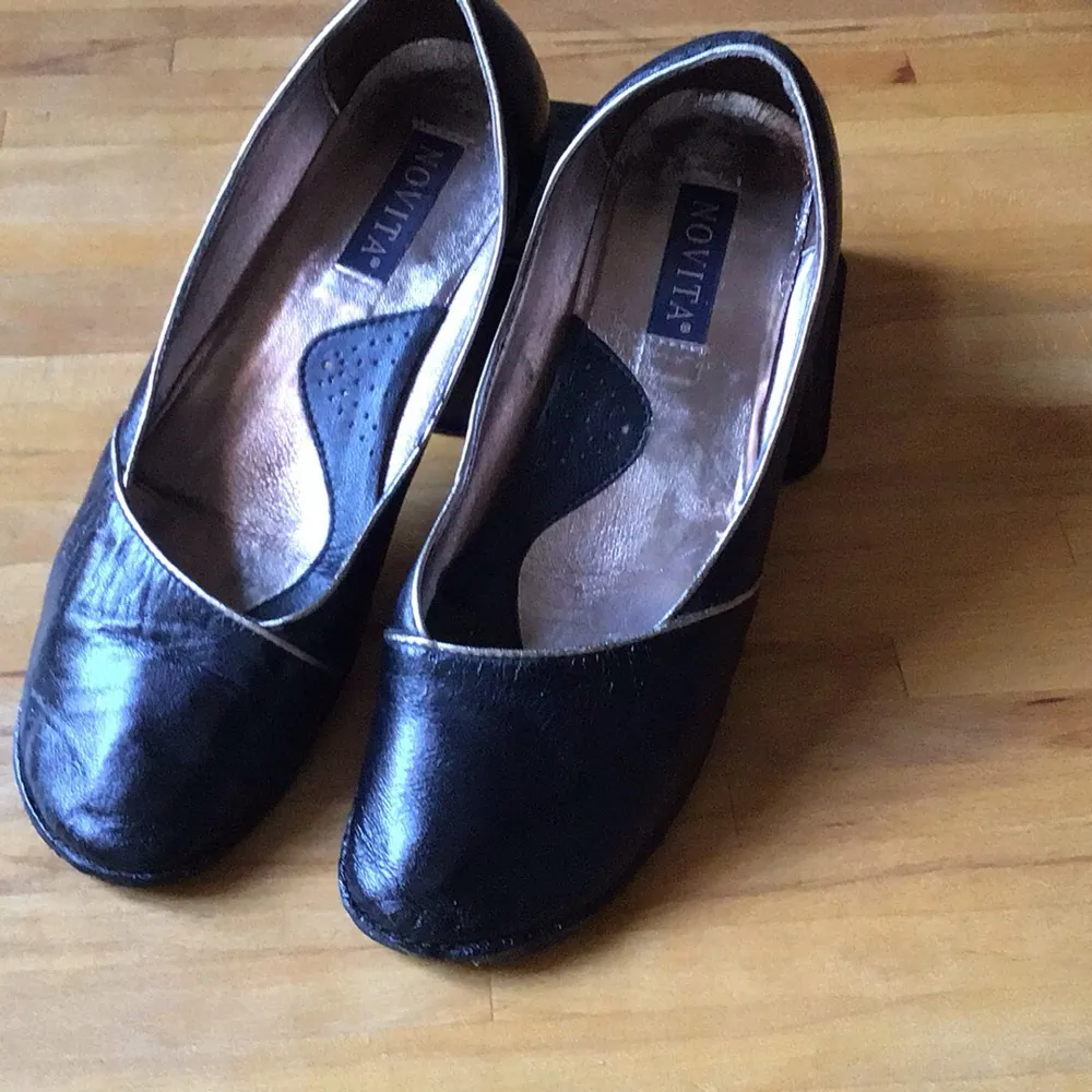 Snygga svarta pumps från Novita i skinn med en elegant design. Skorna har en låg klack och en diskret kantdetalj i kontrasterande färg. Perfekta för en stilren look.. Kengät.