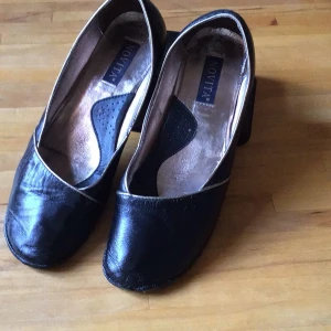 Svarta pumps från Novita - Snygga svarta pumps från Novita i skinn med en elegant design. Skorna har en låg klack och en diskret kantdetalj i kontrasterande färg. Perfekta för en stilren look.