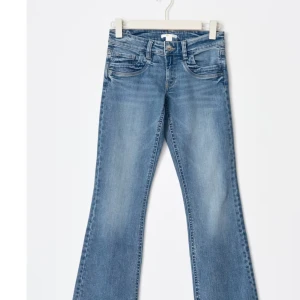 Blå bootcut jeans - Säljer ett par klassiska blå bootcut jeans med fem fickor och knappgylf. Jeansen har en lätt tvättad look och är perfekta för en avslappnad stil. Använda 1 gång 