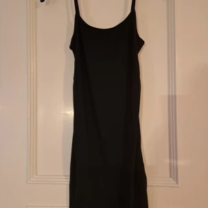Svart klänning från Bershka - Snygg svart klänning från Bershka med smala axelband och en stilren design. Perfekt för en kväll ute eller en speciell tillställning. Klänningen har en enkel och elegant look som är lätt att matcha med accessoarer.