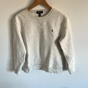 Grå sweatshirt från Ralph Lauren - Säljer en stilren grå sweatshirt från Ralph Lauren med det klassiska logotypbroderiet på bröstet. Tröjan har en rund halsringning och långa ärmar, perfekt för en avslappnad look. Passar både till jeans och chinos.