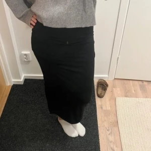 Svart långkjol - Snygg svart långkjol med en tight passform. Perfekt för en stilren look. Kjolen är enkel och elegant, vilket gör den lätt att matcha med olika toppar och accessoarer. Kjolen har även scrunch på sidan.
