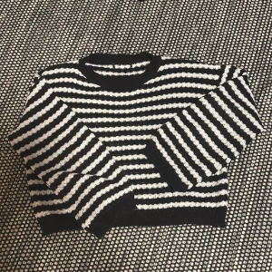Svart och vit randig stickad tröja - Säljer en mysig svart och vit randig stickad tröja med långa ärmar. Perfekt för kyligare dagar och ger en stilren look. Passar bra till både jeans och kjol.