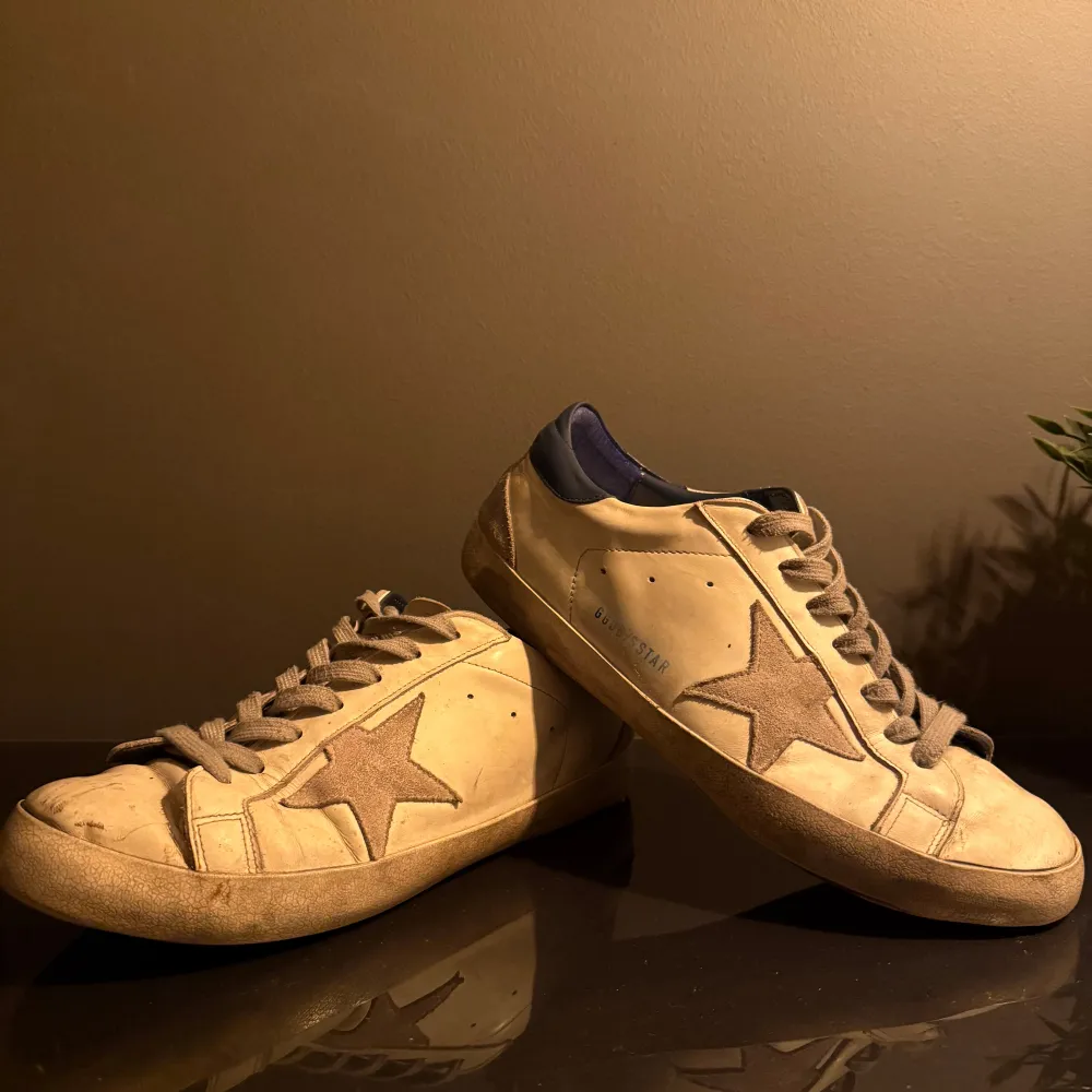 Snygga sneakers från Golden Goose i en klassisk design. Som ni ser på bilderna är de lite slitna men varit inlämnade till skormakare som fixa lite därav priset. Men inget man använder under använing och funkar från punkt A till punkt B. Box medföljer, kom med frågor och funderingar eller egna prisförslag. Kengät.