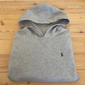 Polo Ralph Lauren Herr Hoodie -  Polo Ralph Lauren Herr Hoodie  Storlek: L (14-16 Barn)  Skick: Nästan som ny, använd en gång  Denna Polo Ralph Lauren hoodie har en klassisk design i en stilren färg. Den är i utmärkt skick, då den endast använts en gång, vilket gör den till ett perfekt tillskott i din garderob. Mått kan ges på begäran.  ✅ Äkta  📩 Öppen för rimliga erbjudanden - vänligen skicka ett meddelande om du har några frågor.  🚚 Frakt - samma dags leverans eller inom 24 timmar, skicka 