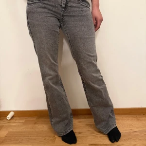Grå lågmidjade jeans - Snygga grå jeansbyxor med en femficksdesign. Byxorna har en bootcut passform och är lowwaist. Dessa är köpta på Gina för 450 kr och är oanvända. Priset kan diskuteras 