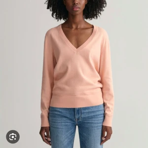 Rosa V-ringad tröja från GANT - Säljer en stilren rosa tröja från GANT med V-ringning. Tröjan har långa ärmar och är tillverkad i ett mjukt material som ger en bekväm passform. Perfekt för en avslappnad look.