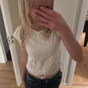 Vit topp från ONLY - Säljer en söt vit topp från ONLY med knytning i midjan. Toppen har korta ärmar och ett diskret prickigt mönster. Perfekt för en avslappnad stil. Den är helt oanvänd och är i storlek 158 men passar utmärkt för en XXs också💞🫶🏻