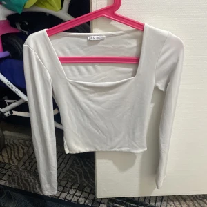 Vit långärmad croppad topp Amisu - Snygg vit långärmad topp från Amisu med croppad passform och fyrkantig halsringning. Tunn och mjuk i materialet, perfekt att styla med höga jeans eller kjol. Enkel och clean look som funkar till många olika outfits.