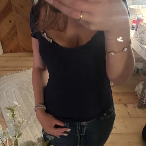 Mörkblå tight topp med spets - Snygg mörkblå topp med tight passform och korta ärmar. Urringningen är djup och har en söt spetsdetalj som sticker fram. 