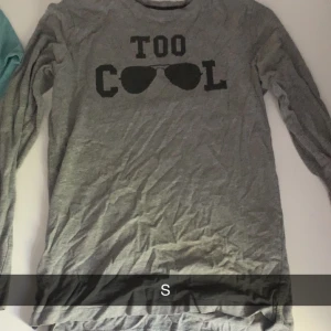 Grå långärmad tröja med tryck - Säljer en grå långärmad tröja i mjuk bomull med svart tryck som säger 'TOO COOL' och har solglasögonmotiv på bröstet. Perfekt för dig som gillar chill och avslappnad stil. Passar till jeans eller mjukisbyxor.
