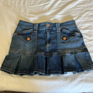 Blå jeanskjol från Reclaimed Vintage - Säljer en blå jeanskjol från Reclaimed Vintage med coola fickdetaljer fram och bak som ger lite y2k vibe! Köpte från Vinted men är i toppen skick. Aldrig använt, bara provat.