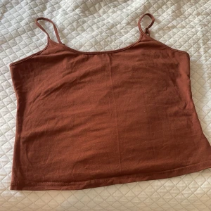 Brun linnetopp från SHEIN - Snygg brun linnetopp från SHEIN i storlek XL. Toppen har smala axelband och ärmlös design, perfekt för varma dagar. Tillverkad i mjuk bomull som känns skön mot huden. Enkel och stilren modell som är lätt att matcha med dina favoritjeans eller shorts.