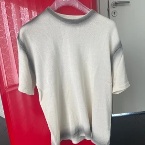 Zara t-shirt  - Snygg beige t-shirt från Zara med grå tonade detaljer vid krage, axlar och nederkant. Modellen är rak och har korta ärmar. Materialet känns mjukt och har en stickad look som ger en chill vibe. 