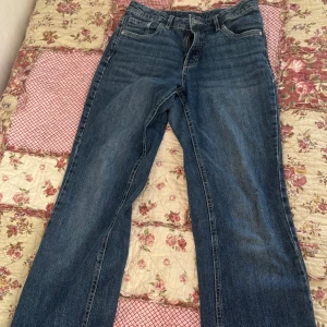 Blå jeans med bootcut - Säljer ett par klassiska blå jeans med bootcut och snygga fickor bak med knappdetaljer. Jeansen har normal passform och midja, och är gjorda i slitstarkt denim. Perfekta för dig som gillar enkel och tidlös stil. Den rosa sömmen på bakfickorna har jag sytt dit själv. Vill bli av med så fort som möjligt så pris kan diskuteras💗