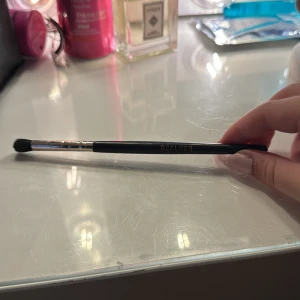 REALHER ögonskuggsborste svart - Snygg ögonskuggsborste från REALHER med svart skaft och metallfäste. Borsten har mjuka, täta strån som gör det enkelt att blenda och applicera ögonskugga med precision. Perfekt storlek för både detaljer och större ytor. Stilren design med guldtext på skaftet.