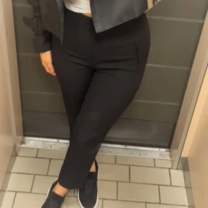 Svarta croppade kostymbyxor - Snygga svarta kostymbyxor med croppad längd och hög midja. Byxorna har en rak passform och är perfekta för en clean och stilren look. Tillverkade i ett mjukt material som ger en skön känsla hela dagen.