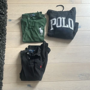 Svart Polo Ralph Lauren hoodie+ grön och svart piké den svarta pikén har ett litet hål som man knappt ser - Svart hoodie från Polo Ralph Lauren med stor vit POLO-logga framtill. Klassisk modell med huva och ribbade muddar. Perfekt för chill dagar och streetwear-stil. Mjuk bomullskvalitet och relaxed fit.