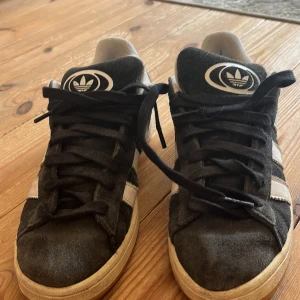 Ett par adidas campus i svart  - En av de är lite slitna och har ett hål i sig men de går fortfarande att använda!