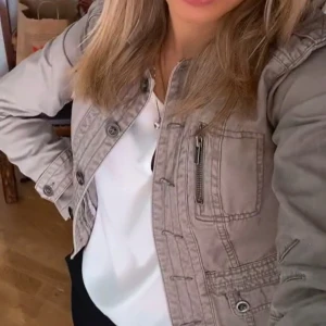 Militärgrön jeansjacka - Säljer en beige/grön jacka. Jackan har klassisk krage och långärmade ärmar, perfekt för vår eller början för höst! Säljer då den är väldigt liten på mig i ärmarna