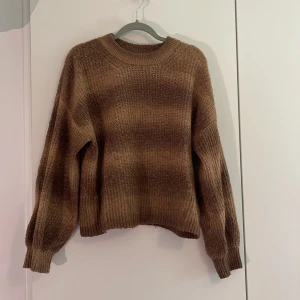 Stickad tröja - Säljer en stickad tröja i olika nyanser av brunt. Tröjan har en rund halsringning, ribbade muddar och långärmade ärmar. Perfekt för dig som gillar chill och avslappnad stil. 