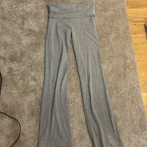 Grå mjukisbyxor från Gina Tricot - Säljer ett par grå mjukisbyxor från Gina Tricot i storlek 146/152. Byxorna har en bred, vikbar midja och raka ben med loose passform. Materialet är mjukt och stretchigt, perfekt för chill dagar eller träning. Snygg enkel design i ljusgrå ton.