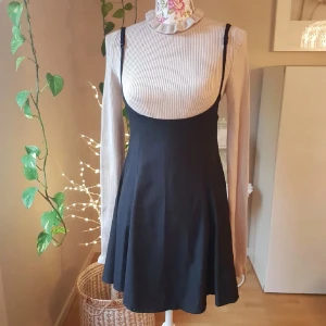 Svart kjol / kortklänning med smala axelband - Stilren svart kortklänning som går under bysten med smala, justerbara axelband och lätt utställd kjol. Klänningen har en enkel design med dragkedja i ryggen och passar perfekt att styla över en tröja eller topp!💞                                              (POLON SÄLJS SEPARAT)