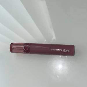 Rom&nd Glasting Color Gloss 05 Dim Mauve - Koreanskt läppglans med glansig finish i mauve-ton. Perfekt för dig som vill ha färg och glans i ett. Säljer då fel färg köpt. Ordinariepris: 149kr