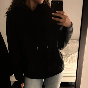 Svart hoodie med tryck från Shein - Säljer en svart hoodie från Shein med ett coolt tryck på baksidan. Trycket föreställer en klassisk staty med rosa detaljer och texten 'Intense Feelings'. Hoodien har en känguruficka och justerbar huva.