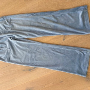 Blå velourbyxor Juicy Couture stl 9/10 - Snygga ljusblå velourbyxor från Juicy Couture med raka, vida ben och fickor med knapp bak. Mjukt material och klassisk Juicy-stil