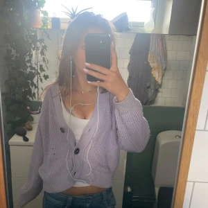 Ljuslila kofta från Lindex, 158/164 - Superfin ljuslila kofta från Lindex med stora knappar framtill. Koftan är stickad, har v-ringning och långa ärmar. Perfekt att slänga över ett linne eller t-shirt för en chill look. Snygg croppad passform som passar till jeans eller kjol.