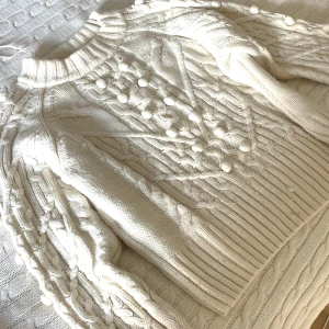 Vit stickad tröja med bollar H&M - Superfin vit stickad tröja från H&M med chunky flätstickat mönster och dekorativa bollar framtill och på ärmarna. Tröjan har ribbad hög hals och muddar, perfekt för kalla dagar. Materialet är en mjuk ullmix som känns både lyxig och skön! Skulle säga att den passar xs-s faktiskt! 