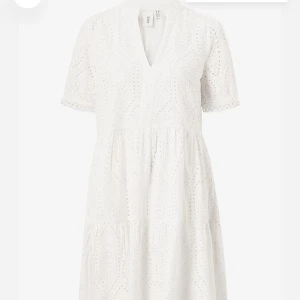 Vit broderad sommarklänning från YAS - Superfin vit kortklänning från YAS med broderade detaljer och v-ringning. Endast använd en gång, jätte fint skick. Klänningen har korta ärmar med spetskant och ett luftigt, flowy fall. Perfekt för sommaren! Nypris 849kr