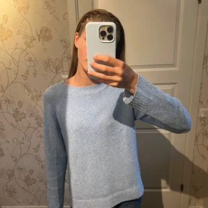 Ljusblå stickad tröja från Vero Moda - Supermjuk ljusblå stickad tröja från Vero Moda med rund halsringning och ribbade muddar. Perfekt för lager-på-lager och chill dagar. Enkel och stilren design som är lätt att matcha med jeans eller kjol.