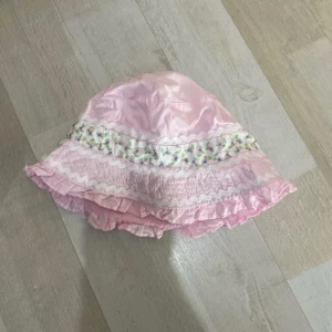 Söt rosa solhatt med volanger - Rosa solhatt med volangkant och dekorativa vita vågband. För barn!