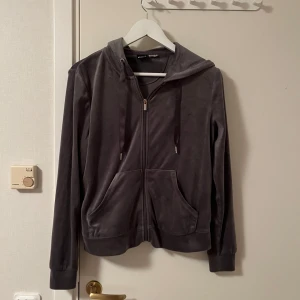 Mörkgrå velour hoodie Gina Tricot - Mysig mörkgrå hoodie från Gina Tricot i mjuk velour. Tröjan har dragkedja framtill, huva med snörning och två stora fickor. Perfekt för chill dagar eller när du vill ha något bekvämt och snyggt på dig.Katt finns i hemmet 